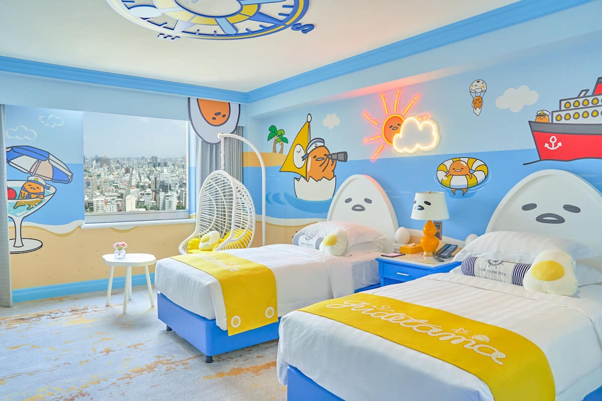 Ein Hotelzimmer mit zwei Betten, Blick auf die Stadt und maritimer Dekoration.