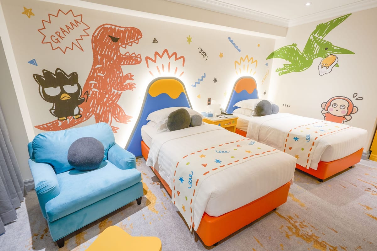 Ein Kinderzimmer mit zwei Betten, einem blauen Sofa und verspielten Wanddekorationen.
