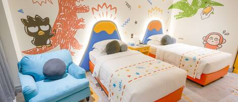 A children's bedroom with two beds, a blue sofa, and playful wall decorations.