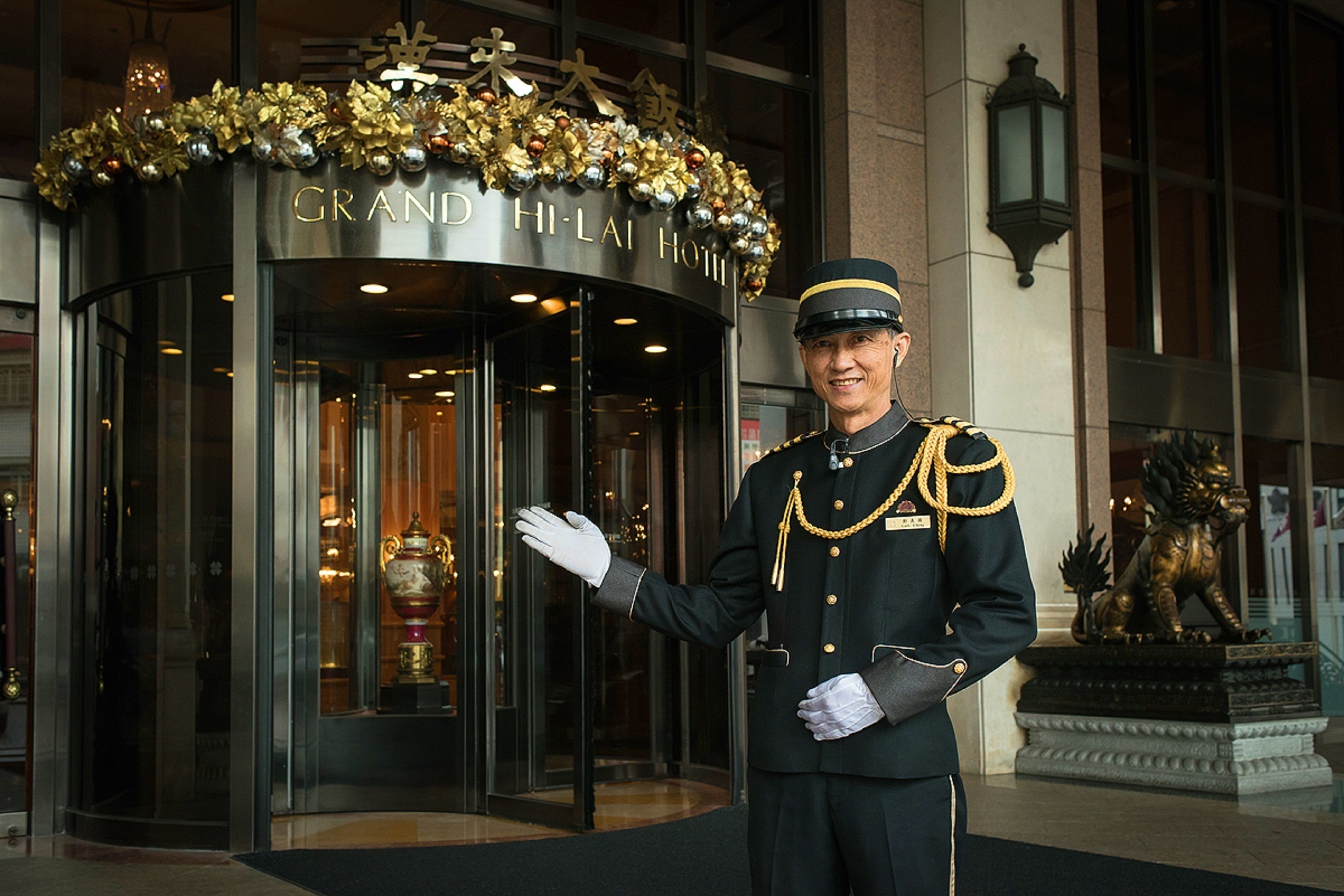 A Grand Hi-Lai Hotel entrance with a grandiose facade, a welcoming staff member, and a lion statue.
