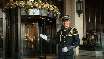 Entrada del Grand Hi-Lai Hotel con una fachada imponente, un miembro del personal amable y una estatua de león.