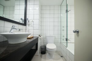 Un baño moderno con lavamanos blanco, inodoro y ducha con mampara de vidrio.