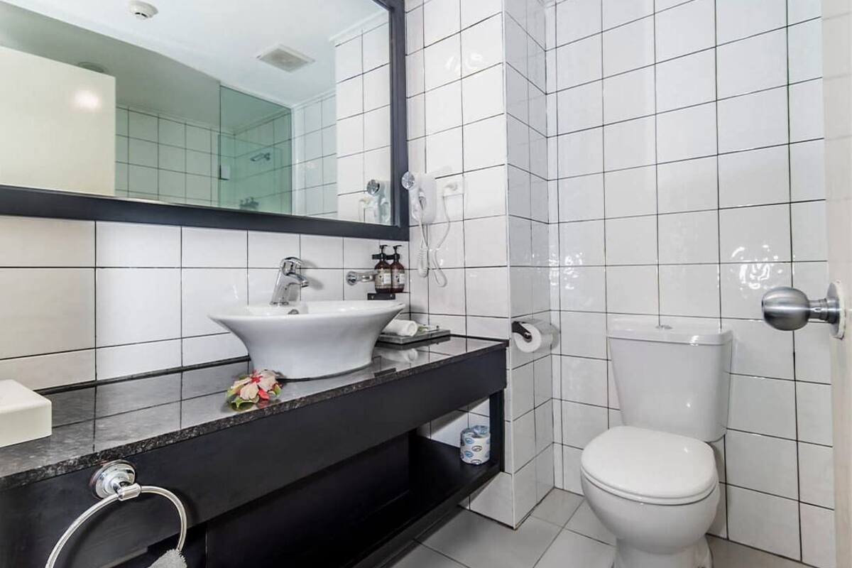 A modern bathroom with a black countertop, white sink, and toilet.