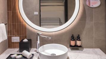 Un bagno moderno con uno specchio rotondo, un lavabo a incasso e un porta asciugamani.