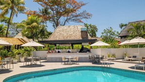 A pool area with a barbecue setup, outdoor seating, and a view of the surrounding greenery. - Tanoa International Hotel (Nadi)