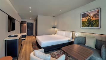 Una habitación de hotel moderna con una cama, un escritorio, un sofá y una mesa de comedor.