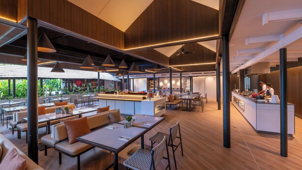A modern restaurant with wooden paneling, pendant lighting, and a central bar area. - Tanoa International Hotel (Nadi)
