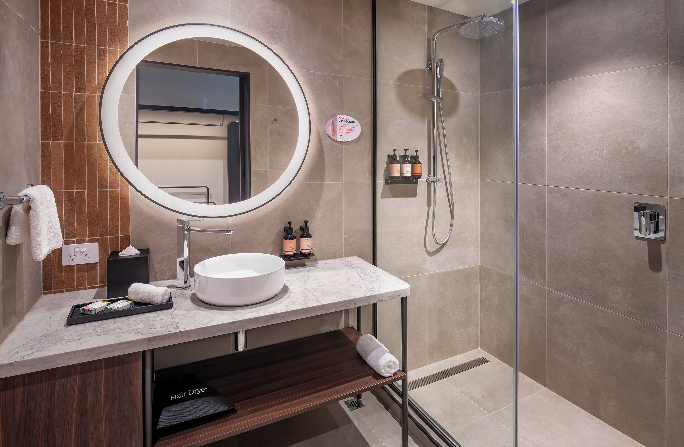 A modern bathroom with a round mirror, a sink, and a shower.