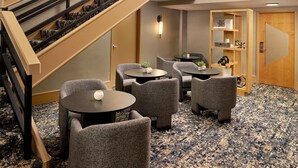 Eine Hotelhalle mit Treppe, Sitzgelegenheiten und einer Rezeption.