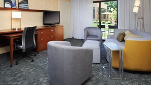 Ein Hotelzimmer mit Schreibtisch, Fernseher, Sofa und Sessel.