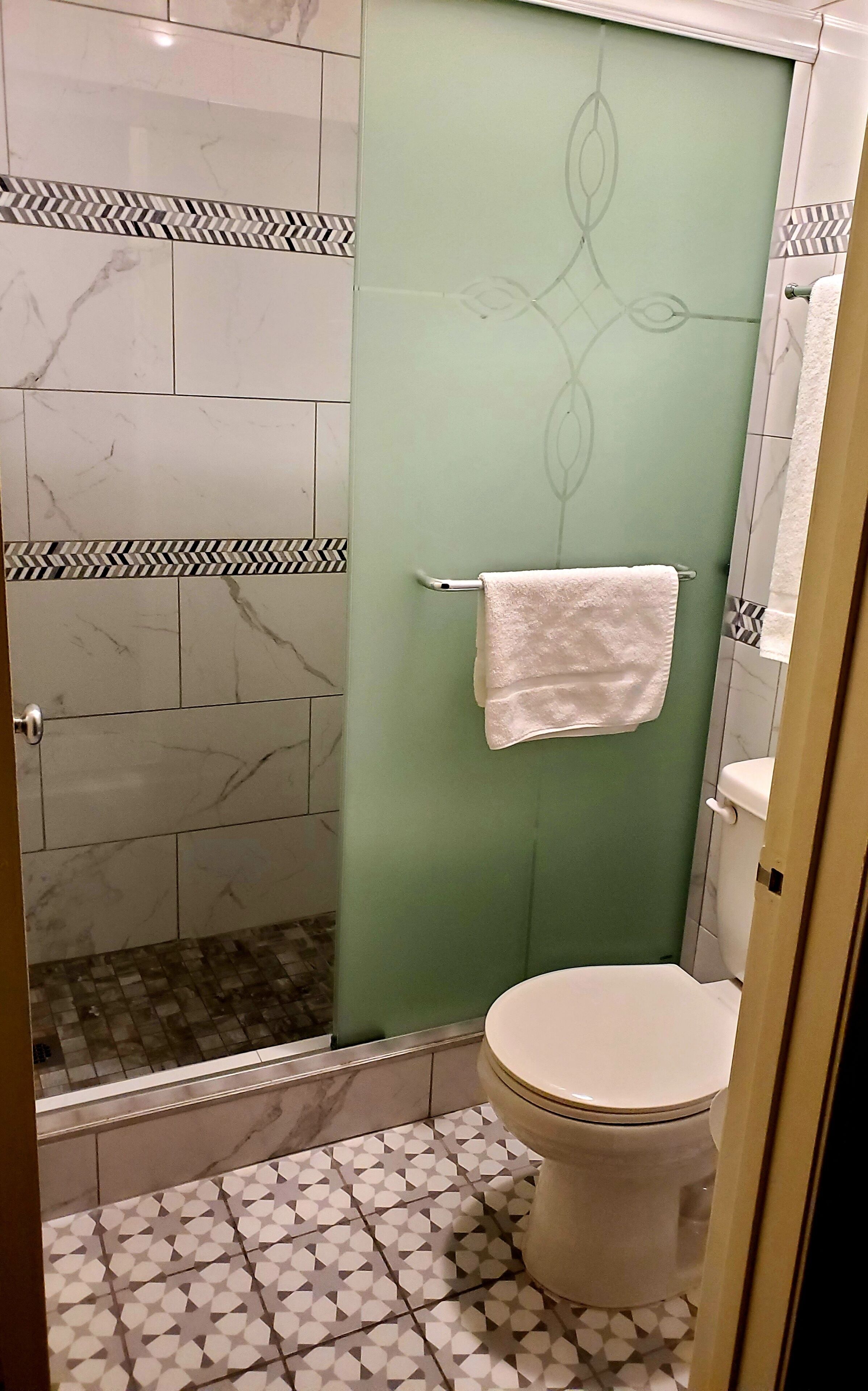 A bathroom with a shower, toilet, and a towel rack.