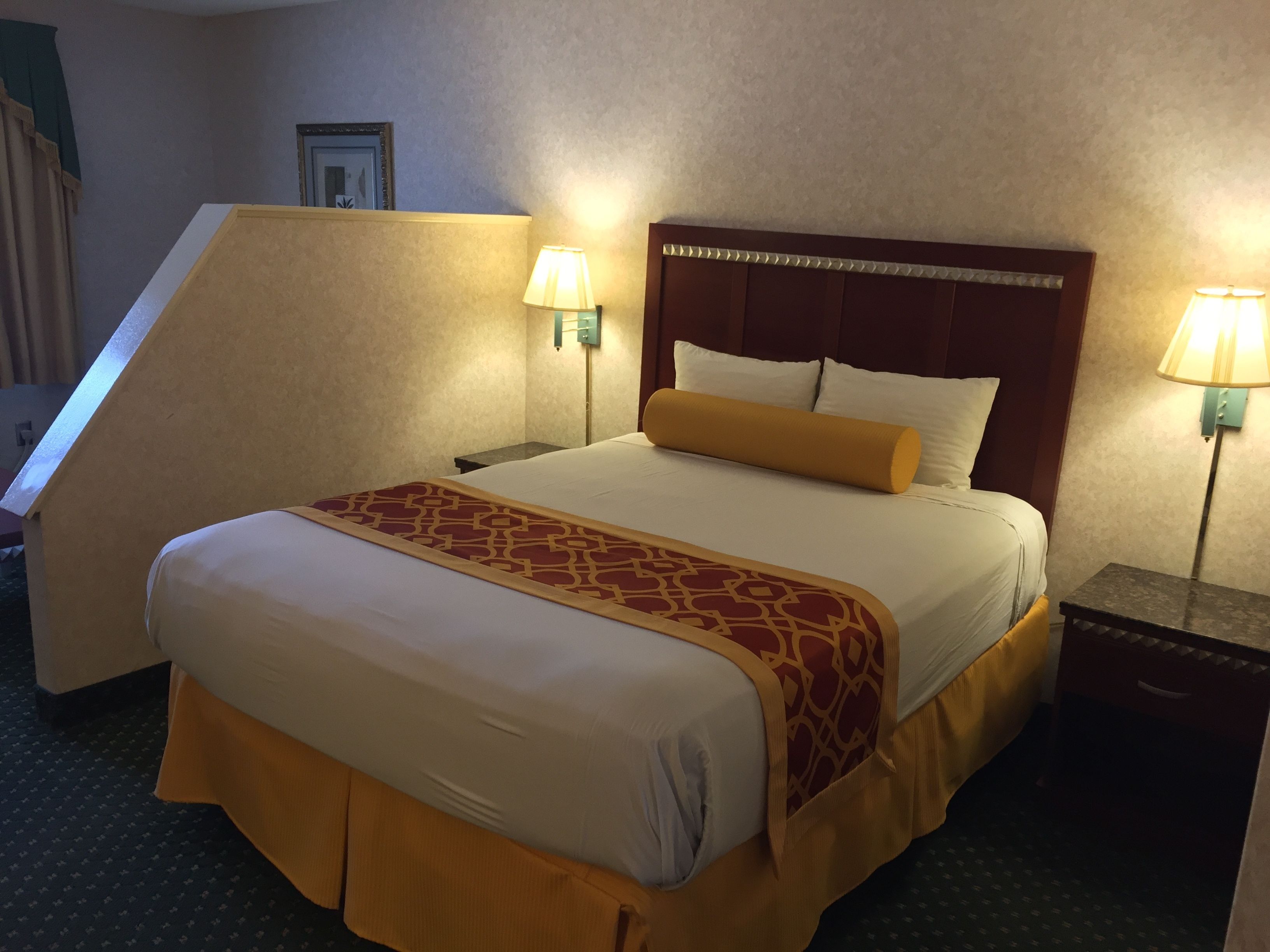 Une chambre d’hôtel avec un grand lit, deux lampes de chevet, une tête de lit et une petite table de chevet.