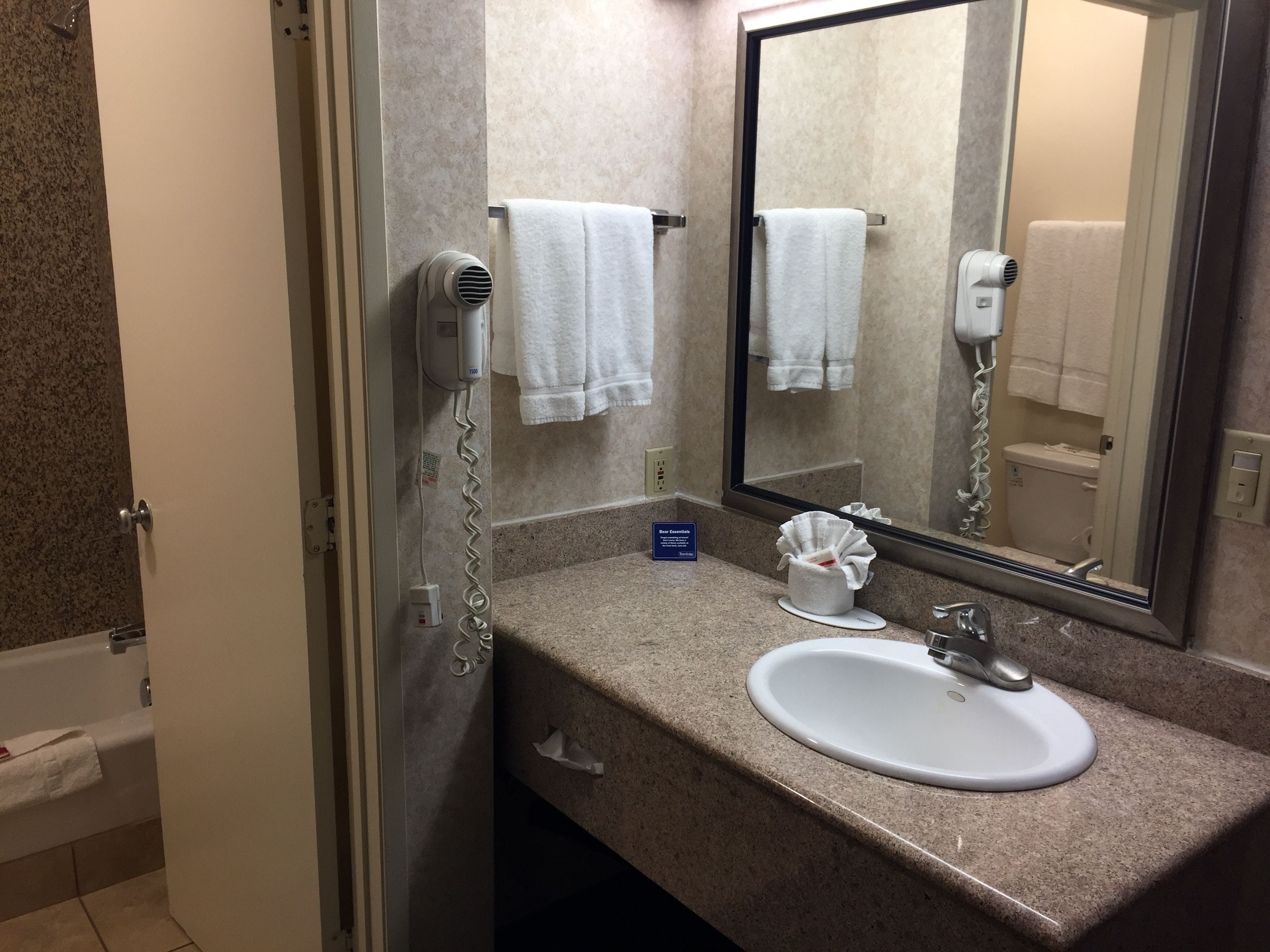 A bathroom with a sink, mirror, towel rack, and hair dryer.