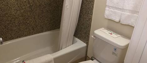 A bathroom with a bathtub, toilet, and shower curtain.