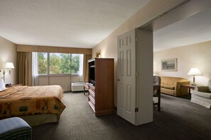A hotel room with a bed, a dresser, a television, a sofa, and a chair. - Days Inn by Wyndham Sidney OH (Sidney)