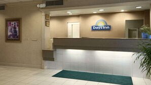 Un espace d’accueil avec une enseigne « Days Inn », un comptoir de réception, une moquette verte et un tableau encadré au mur.