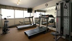 Une salle de sport d’hôtel équipée de tapis de course, d’un vélo d’appartement et d’une machine de musculation.