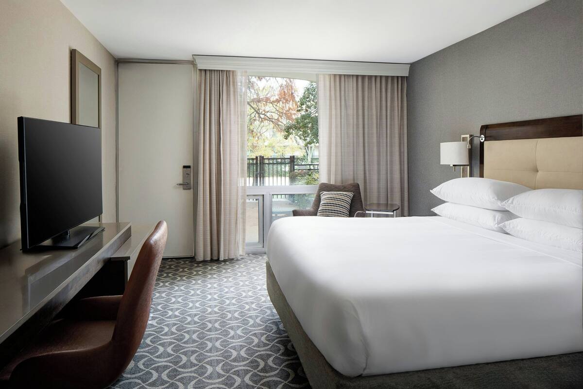 Una habitación de hotel con una cama, televisor, escritorio y una silla.