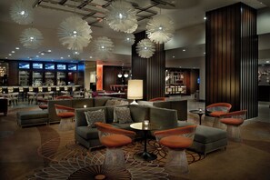 A modern hotel lobby with a bar area, seating arrangements, and decorative lighting. - Marriott St. Louis Airport (St. Louis)