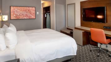 A hotel room with a large bed, a desk with a chair, a television, and a map on the wall.