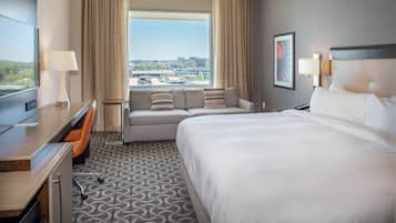 A hotel room with a large bed, a sofa, a desk, and a TV.
