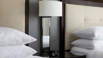 A hotel room with a bed, a bedside table with a lamp, and a control panel.