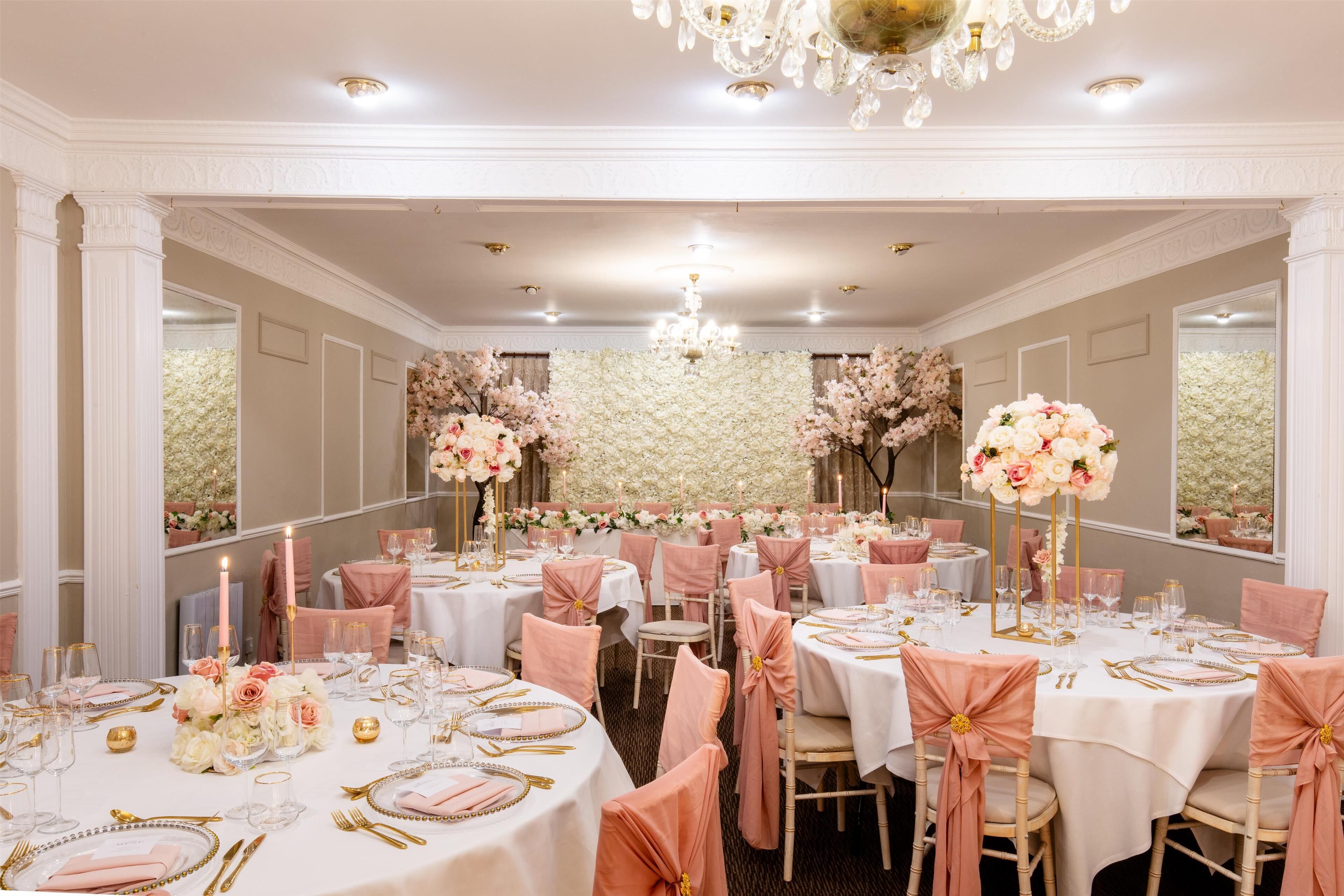 Uma sala de banquetes com mesas redondas, cadeiras cor-de-rosa e arranjos florais.