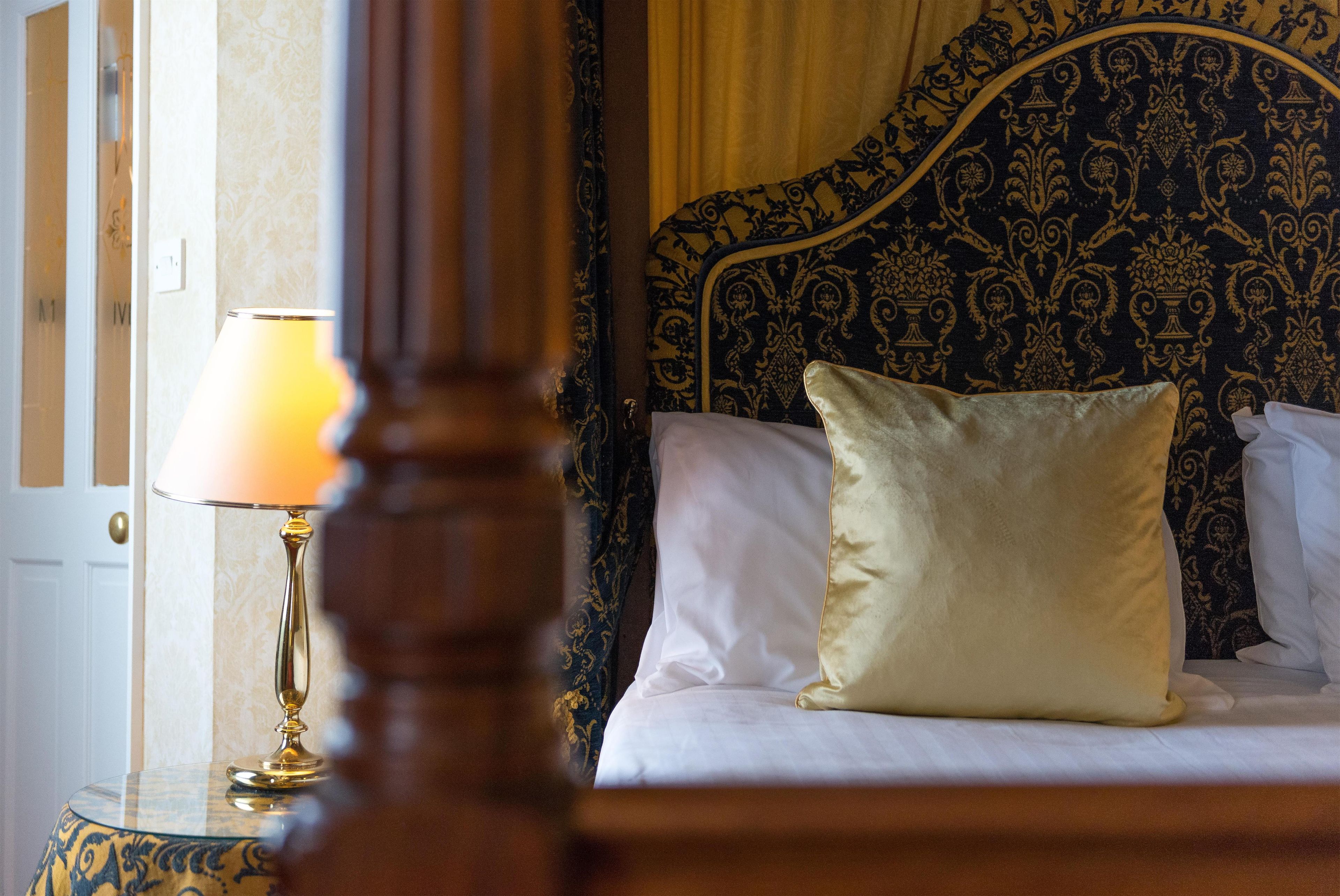 Una habitación de hotel con una cama, una mesita de noche y una lámpara.
