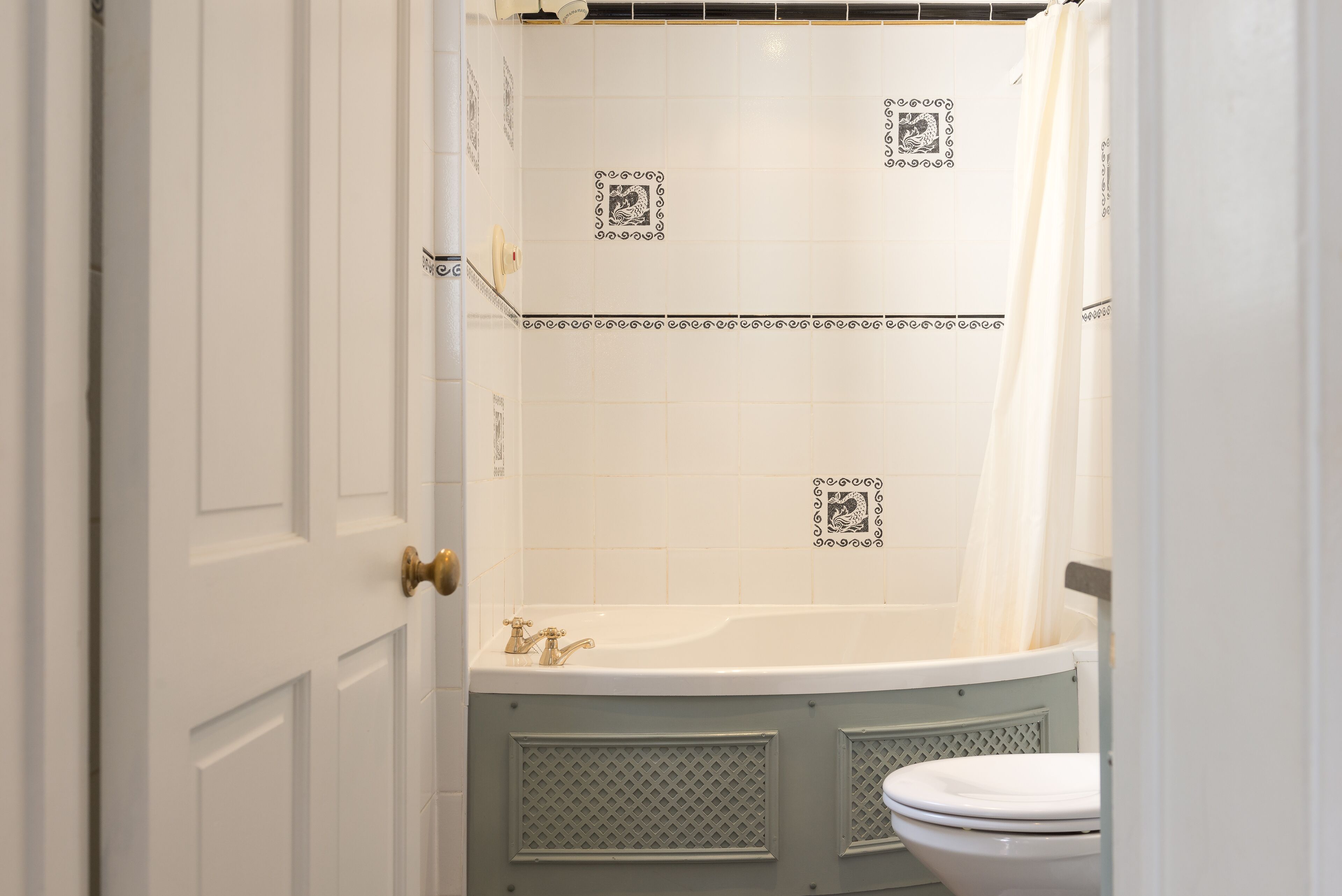 A bathroom with a white door, a bathtub, and a toilet.