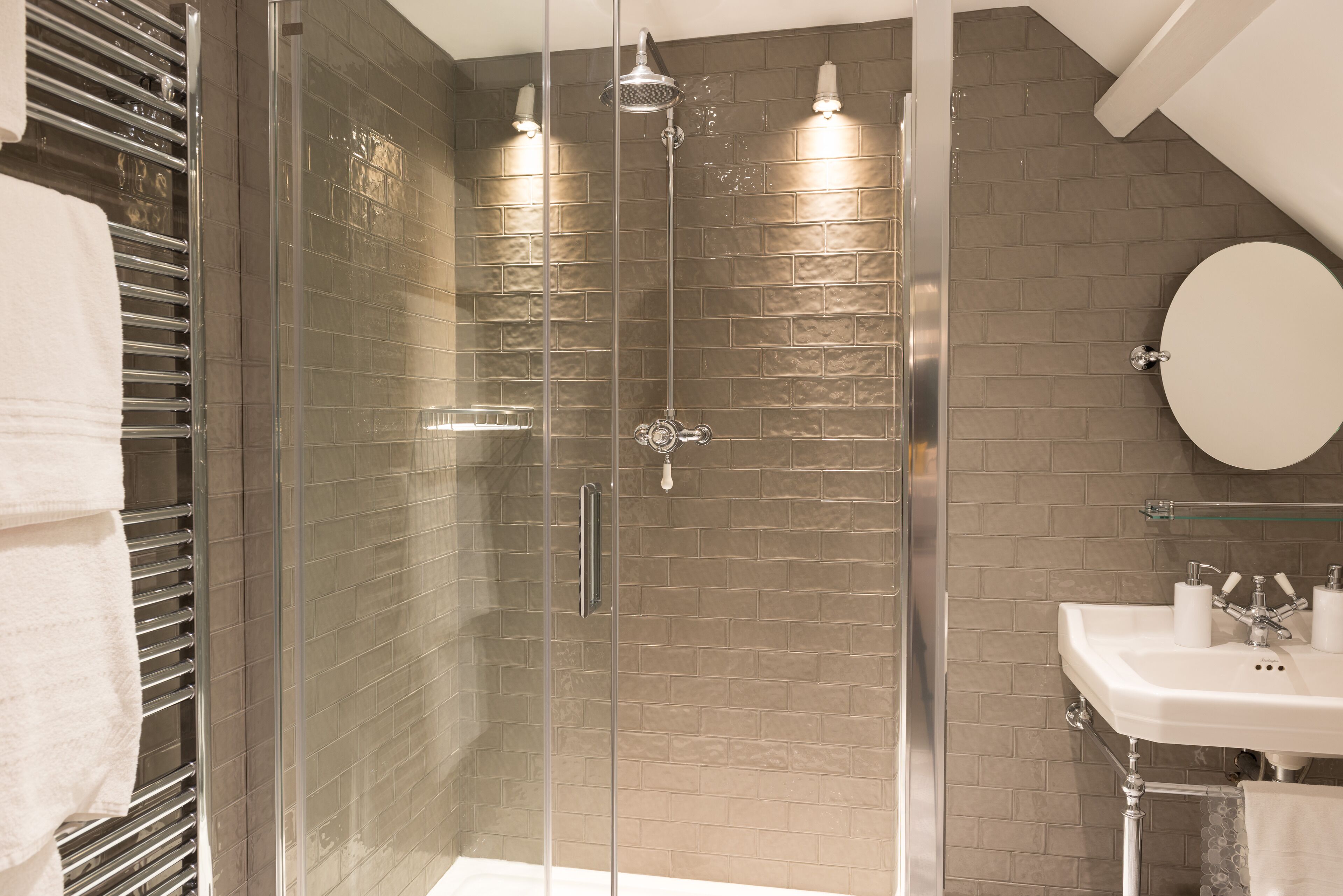 A modern bathroom with a glass-enclosed shower, a white sink, and a large mirror.