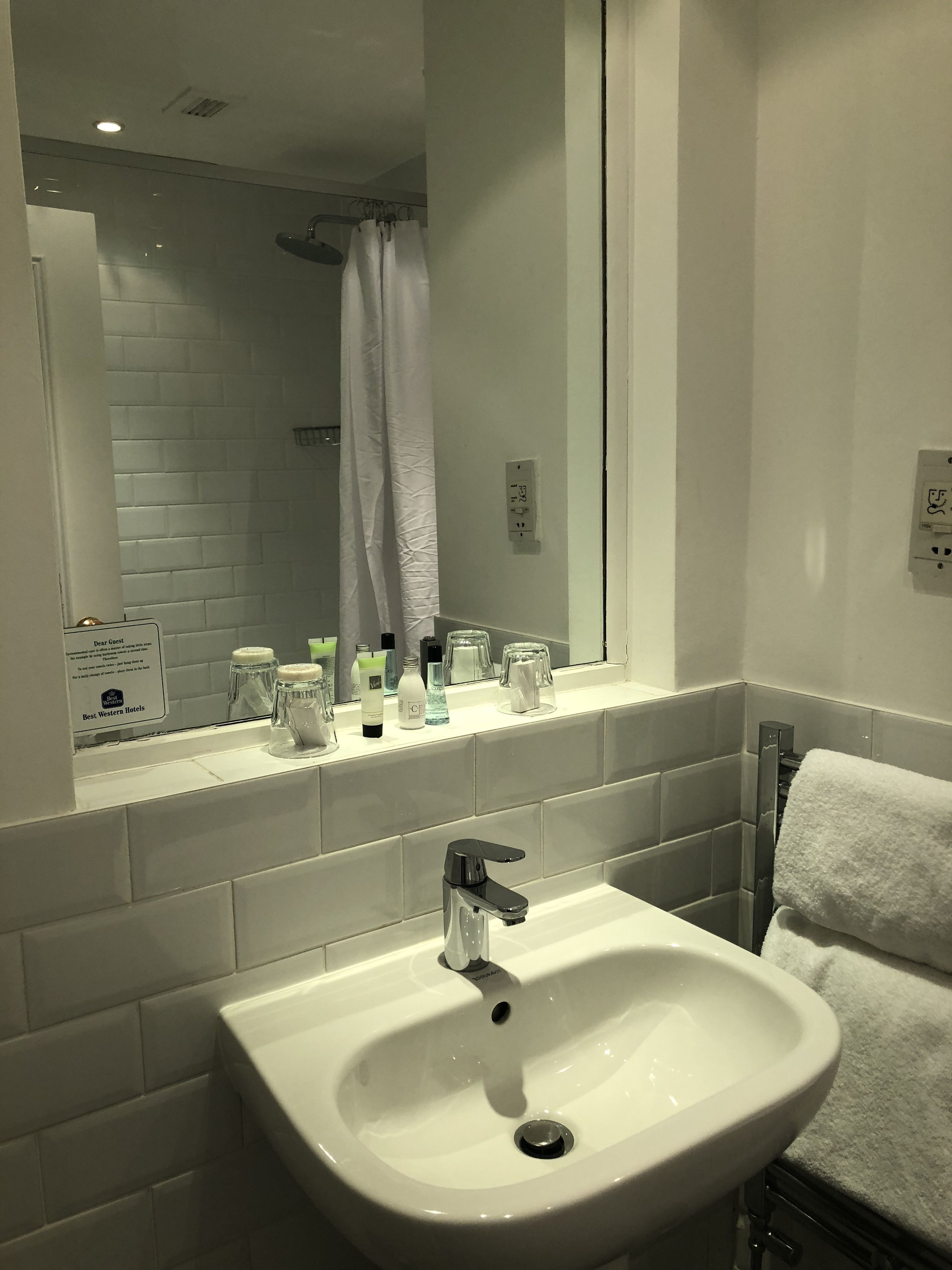 Une salle de bain avec un lavabo blanc, un miroir et un porte-serviettes.