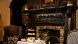 A dining area with a brick fireplace, a three-tiered dessert stand, and a table set with tea service. - Best Western Red Lion Hotel (Salisbury)