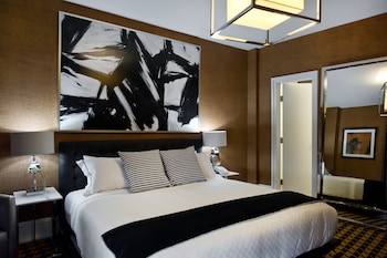 A modern living room with a red sofa, a fireplace, and abstract wall art. at Ameritania Hotel at Times Square