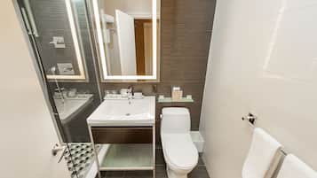 A modern bathroom with a glass shower enclosure, a white sink, and a toilet.