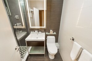 A modern bathroom with a glass shower enclosure, a white sink, and a toilet. - Ameritania Hotel at Times Square (New York)
