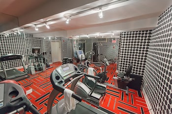 A conference room with multiple black office chairs, a tall pillar with lights, a patterned carpet, and a flat-screen TV on the wall. at Ameritania Hotel at Times Square
