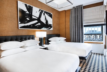 A lobby with red leather chairs, a central table with a vase of red roses, and a modern interior design. at Ameritania Hotel at Times Square