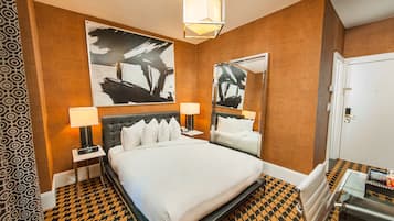 A hotel room with a large bed, two bedside tables with lamps, a mirror, and a patterned floor.