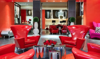 A bar area with a large abstract artwork, multiple bottles of alcohol, and two red lamps. at Ameritania Hotel at Times Square