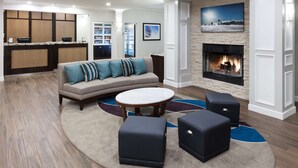 A modern living room with a sofa, ottomans, and a round coffee table. - Homewood Suites by Hilton Seattle-Tacoma Airport/Tukwila (Tukwila)