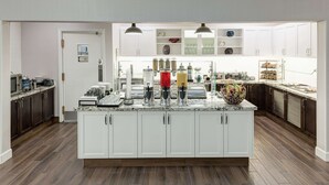 A modern kitchen with a large island, white cabinetry, and a variety of appliances and utensils. - Homewood Suites by Hilton Seattle-Tacoma Airport/Tukwila (Tukwila)