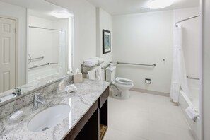 Features a spacious layout with a large sink, separate toilet area, shower with a glass door and grab bar.