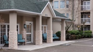 A building with a beige facade, stone pillars, and a green roof. There are outdoor seating areas with chairs and a sign displaying the number 6955. - Homewood Suites by Hilton Seattle-Tacoma Airport/Tukwila (Tukwila)