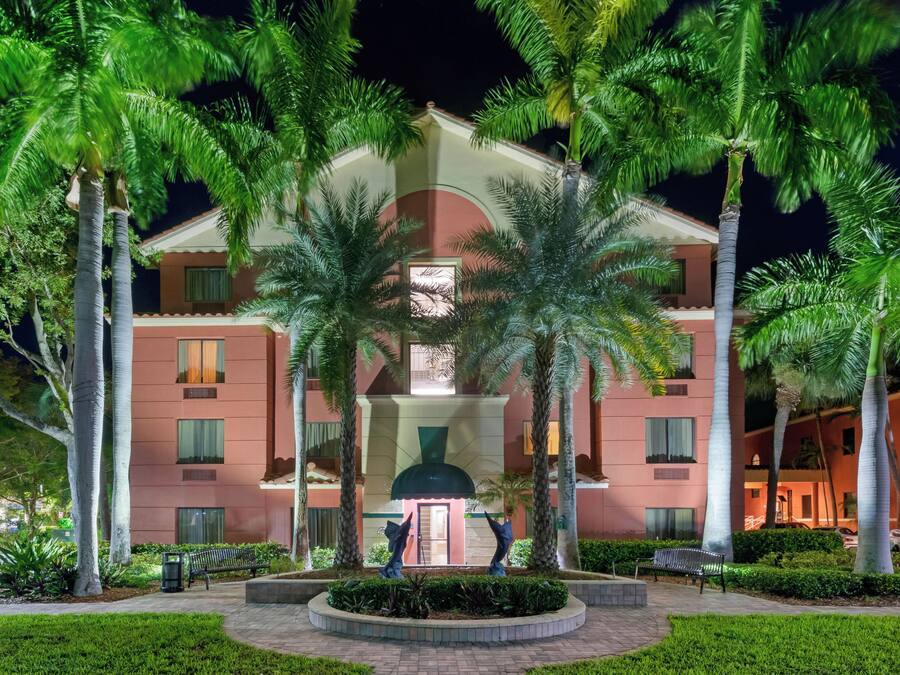A hotel with a central courtyard, palm trees, and a statue.