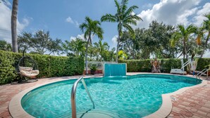 A swimming pool with a metal ladder, surrounded by a brick patio and palm trees. - Best Western Plus Palm Beach Gardens Hotel & Ste & Conf Ctr (North Palm Beach)