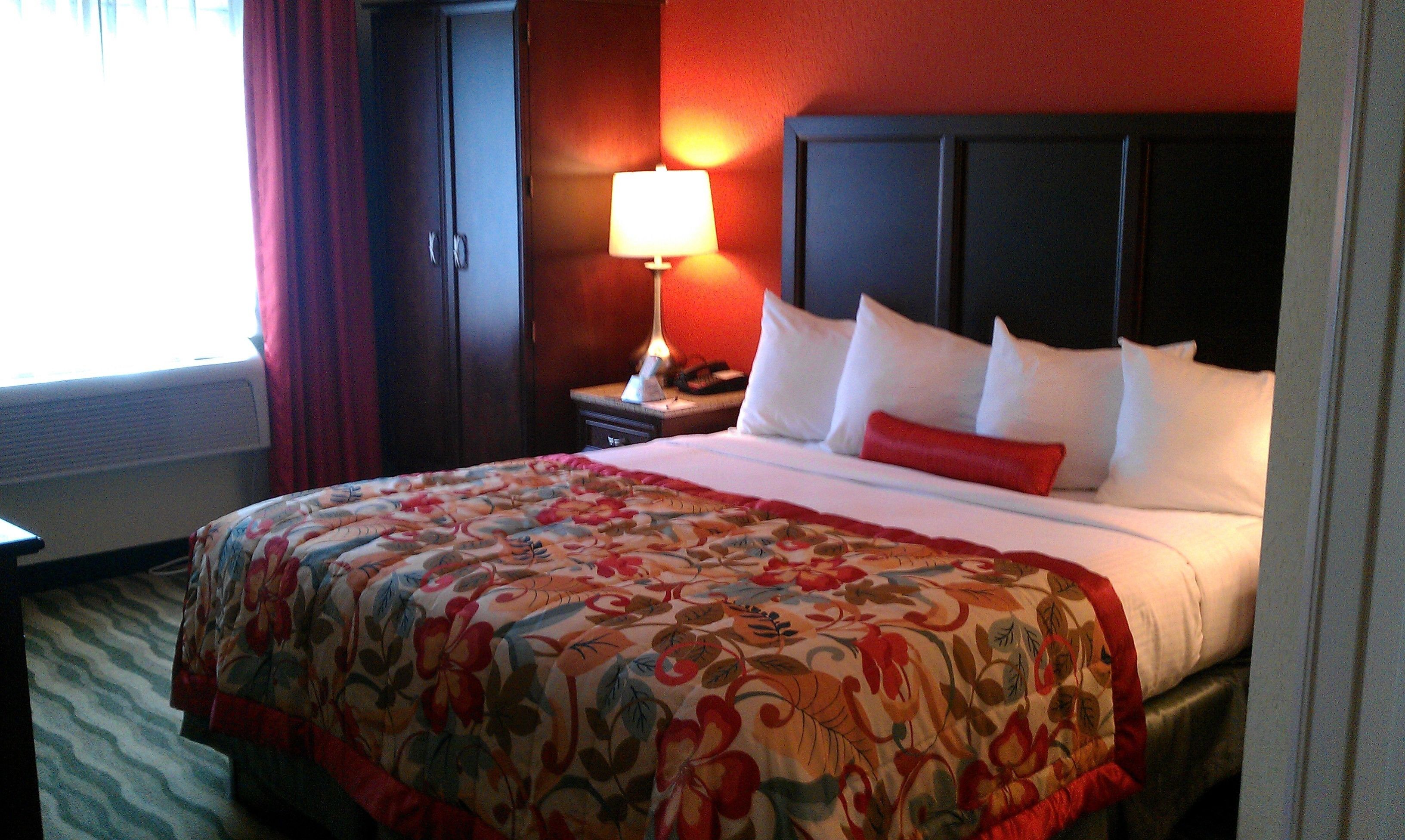 Una habitación de hotel con una cama grande, una mesita de noche, una lámpara y un armario.