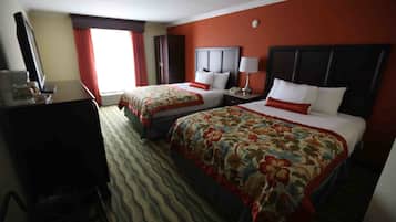 A hotel room with two beds, a desk, a chair, a TV, and a window with curtains.