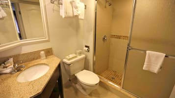 Un baño con lavamanos, inodoro y ducha envuelta en vidrio.