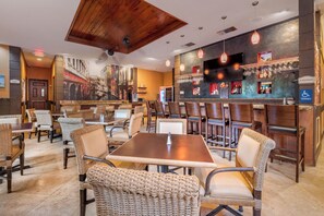 A restaurant with wicker chairs, a bar area, and a mural on the wall. - Best Western Plus Palm Beach Gardens Hotel & Suites and Conference Ct (North Palm Beach)
