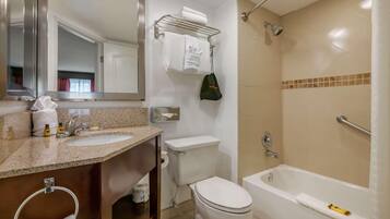 A bathroom with a sink, toilet, and bathtub. There is a towel rack with towels and a bag hanging on it.
